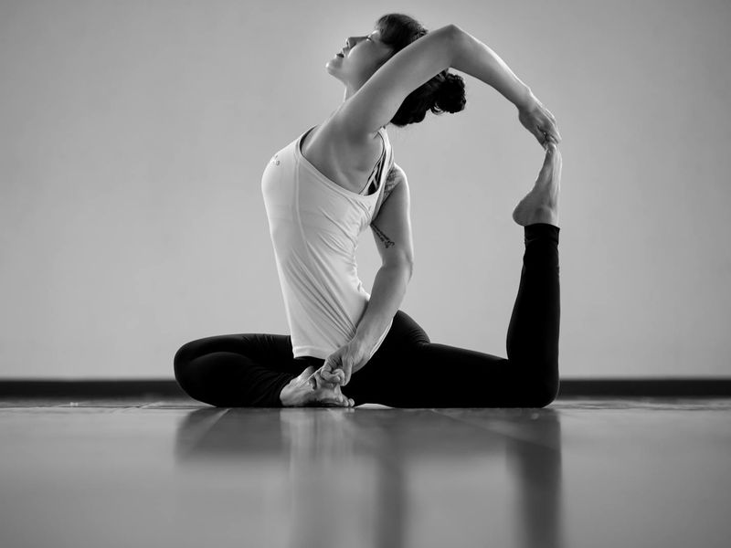 Woman in a dynamic yoga flow pose in a minimalist studio.